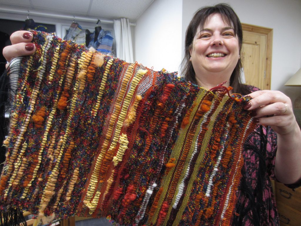 Woman holding a handmade brown, green and red-stripedweaving