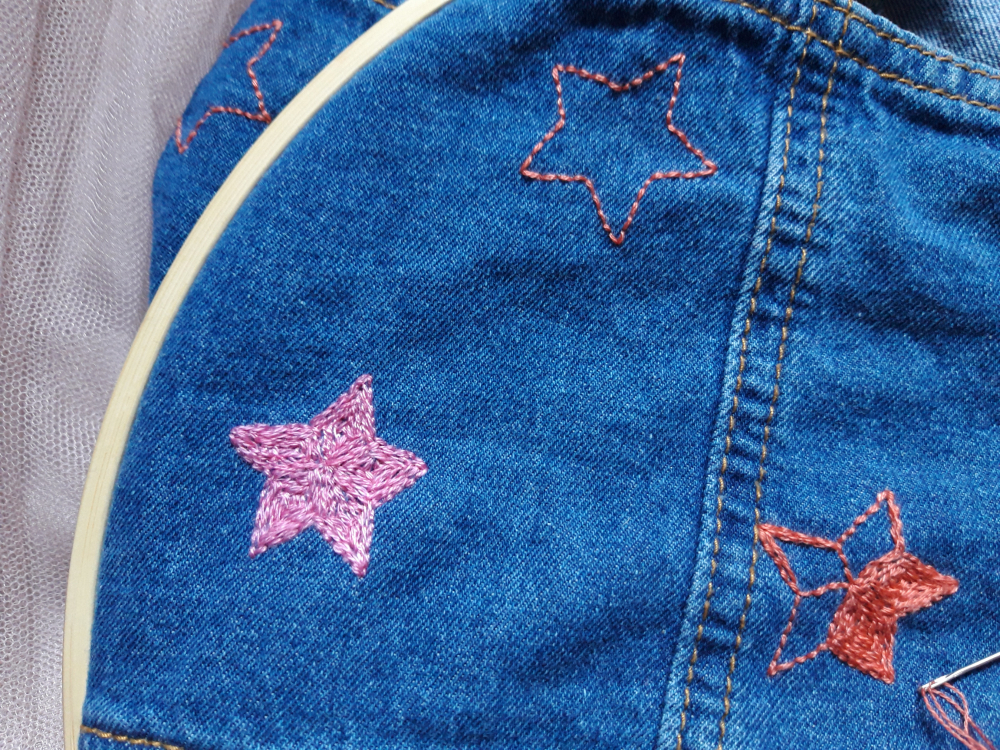 Pink and orange embroidered stars on blue denim